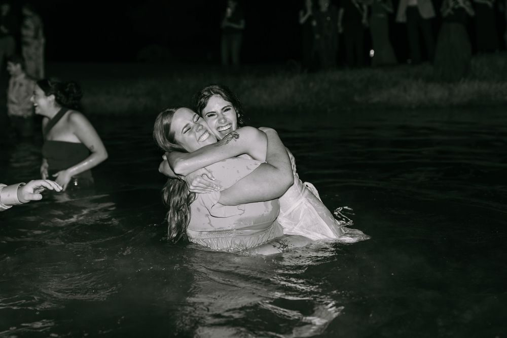 A vintage black and white photograph shows two people embracing while standing in water at night.