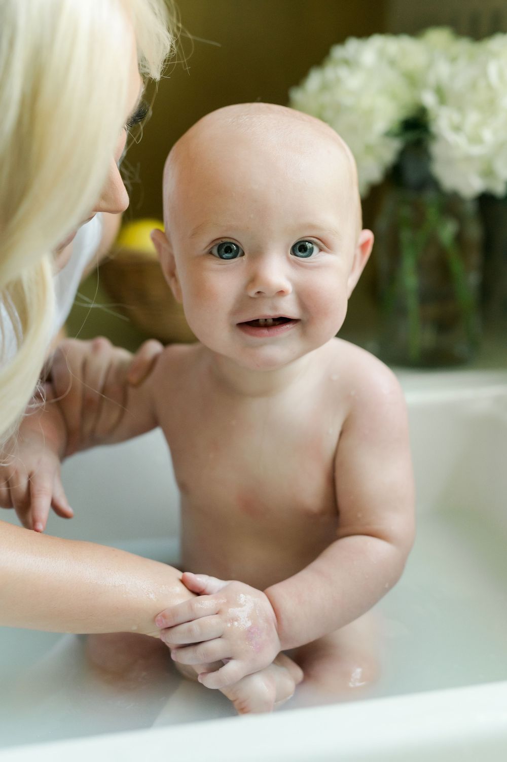 A sequence of an infant bath time showing a baby being lovingly bathed in a pristine white tub.