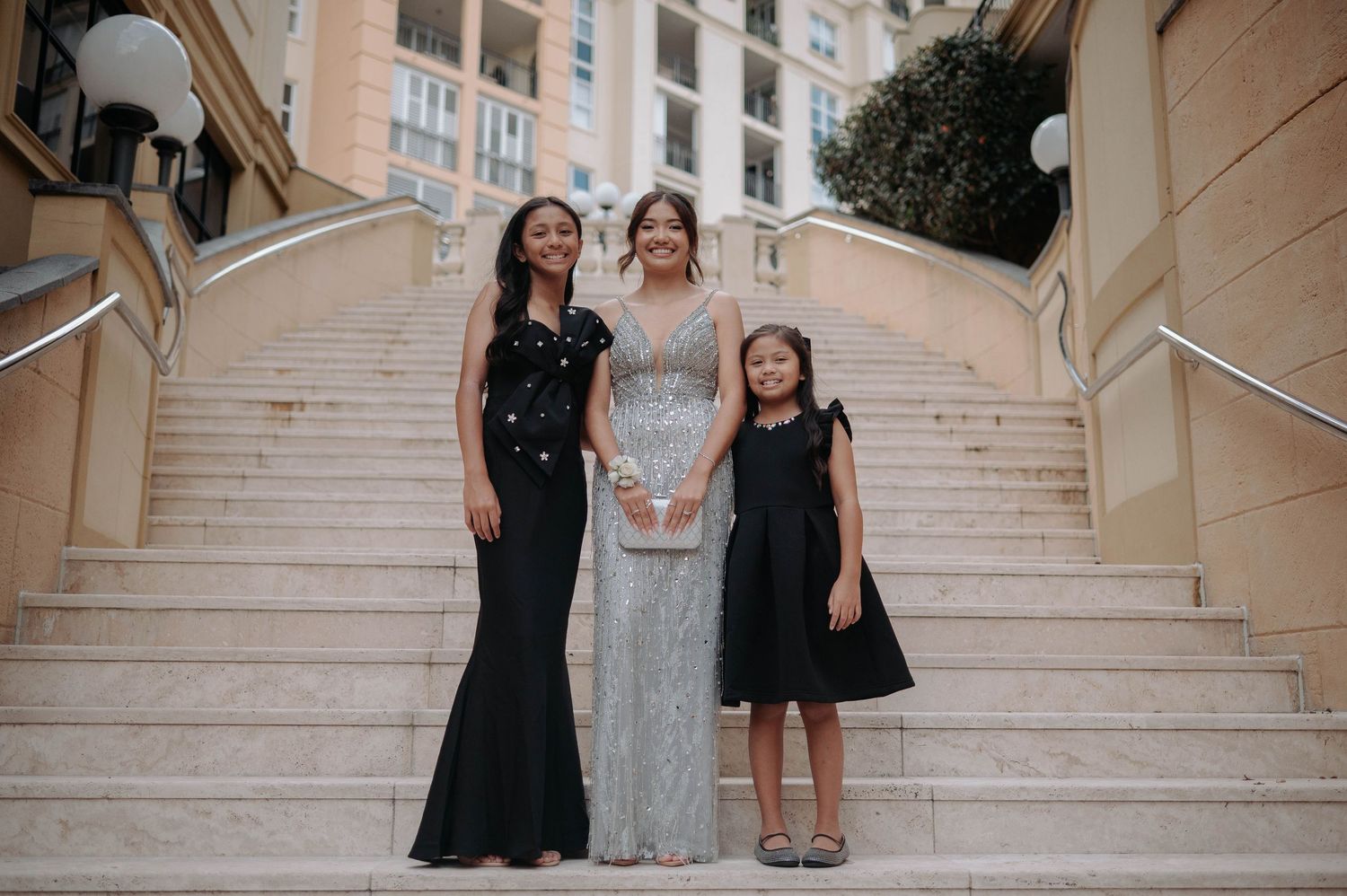 A group poses for a wedding photo on an elegant beige marble staircase.