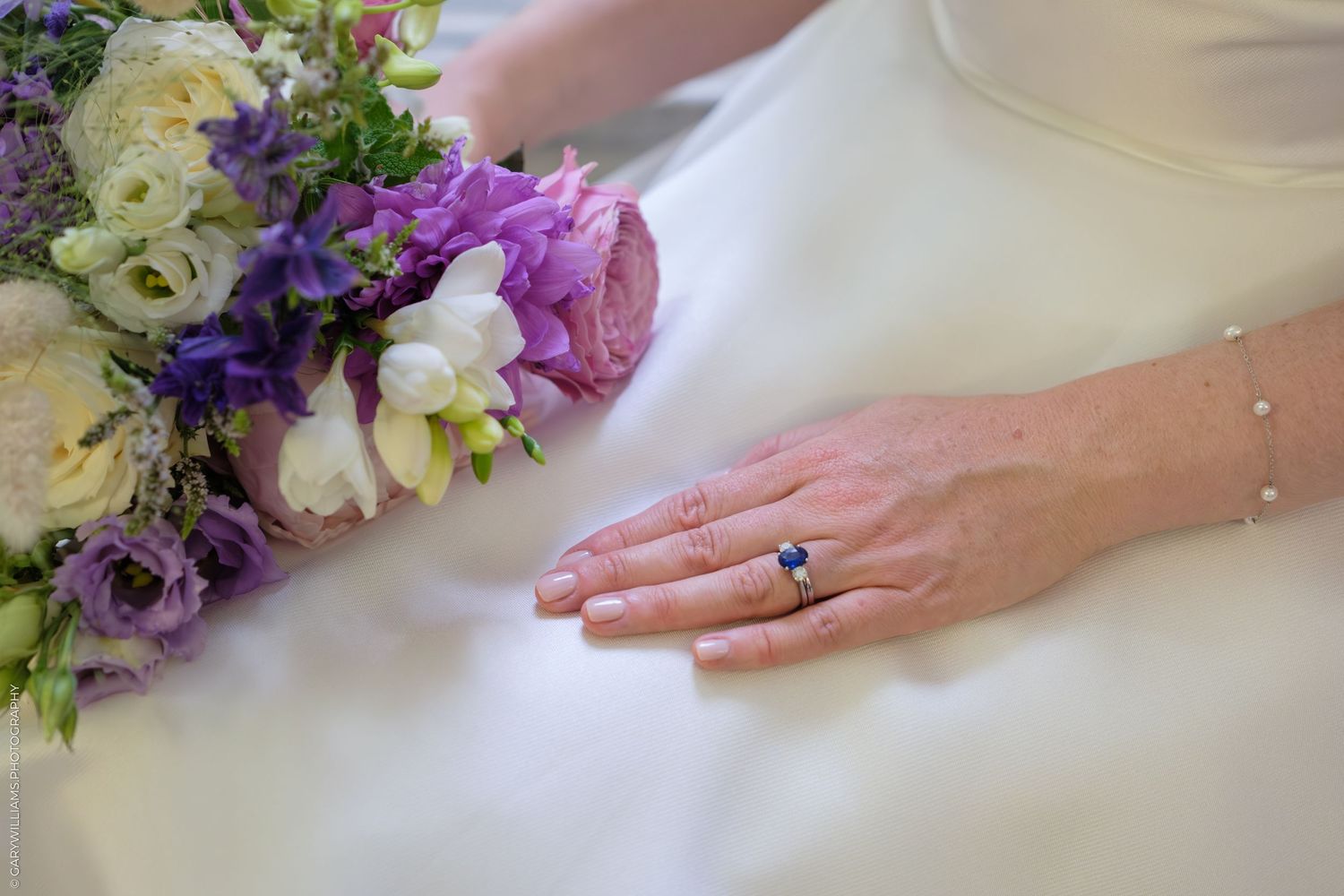 A couple in formal wedding attire walk down an elegant marble hallway with ornate architectural details.