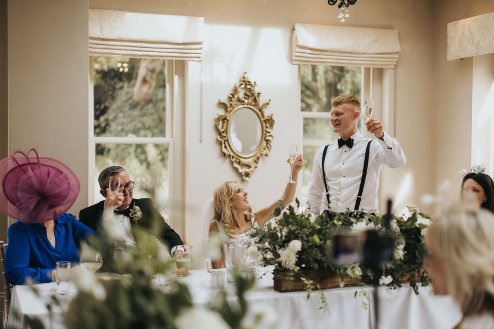 Wedding reception speech moment at an elegant with floral centerpieces and ornate mirror decor at Cleatham Hall.