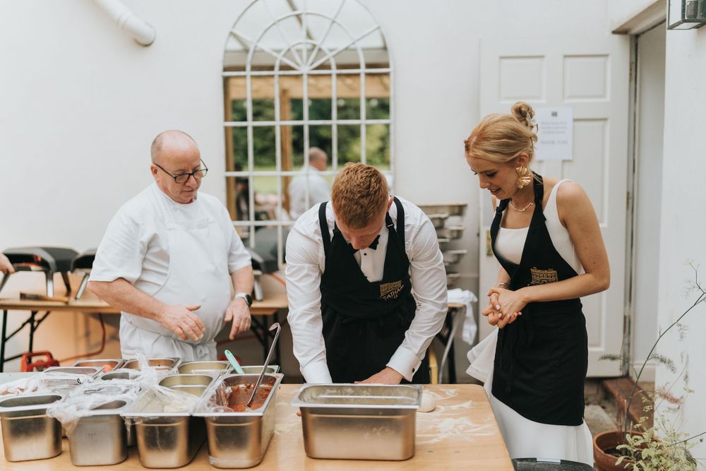 Bride and groom in cooking aprons stood with a chef at Cleatham Hall - image captured by Grimsby photographers.