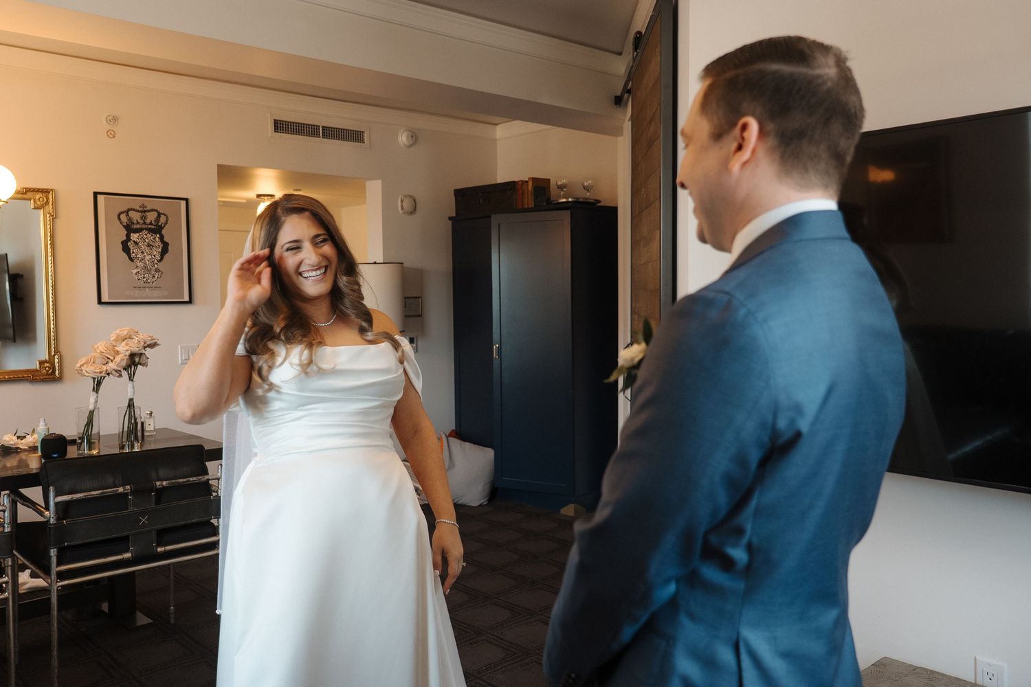 Two people sharing a joyful first dance moment at an indoor wedding reception while guests watch and celebrate.