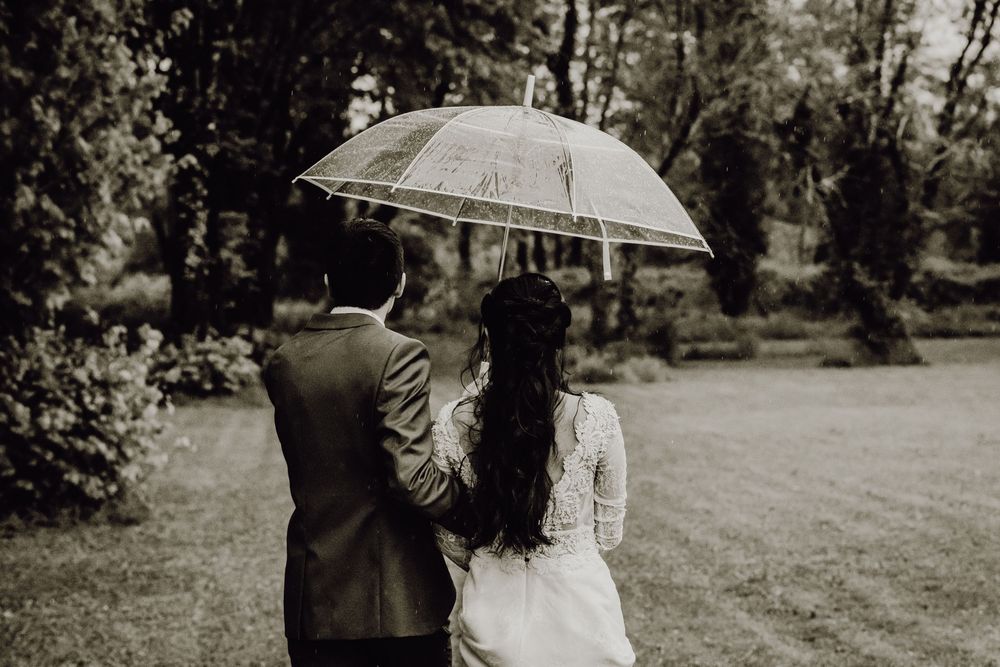 A couple shares a romantic moment under a lace umbrella during their outdoor wedding photo session.