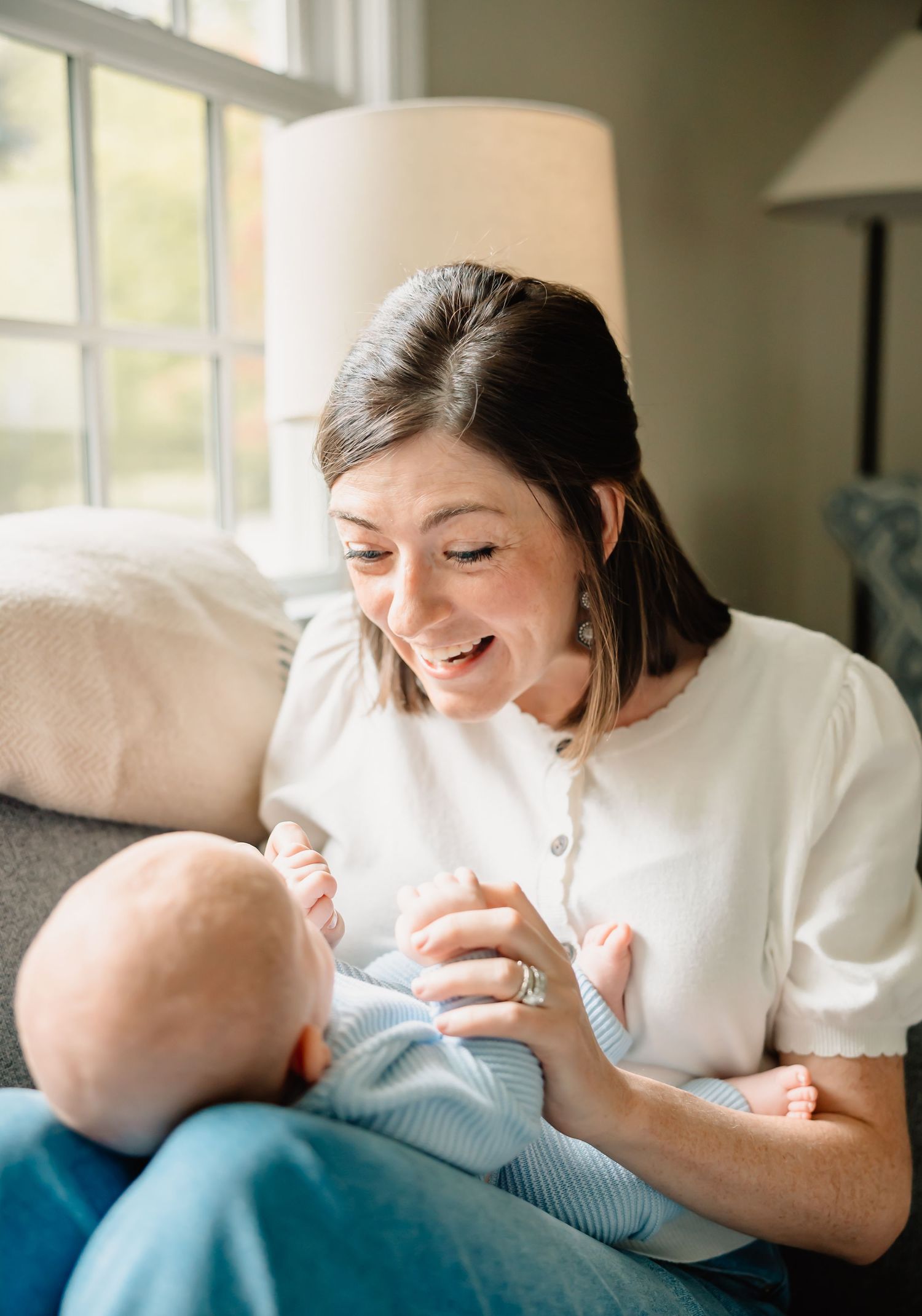 A tender moment between parent and infant sitting by a window in soft natural light.