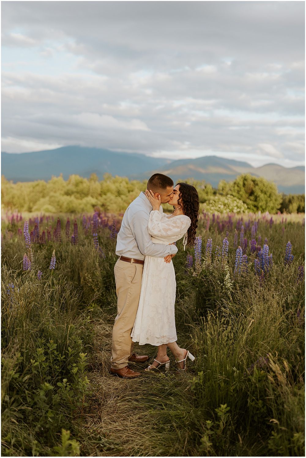 A NH couple taking engagement photos in a lupine flower field