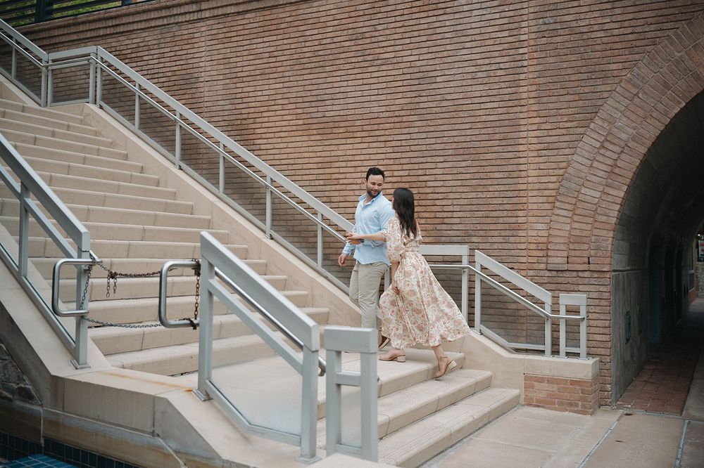 A romantic moment captured on stone steps with a brick archway backdrop near an urban waterway.