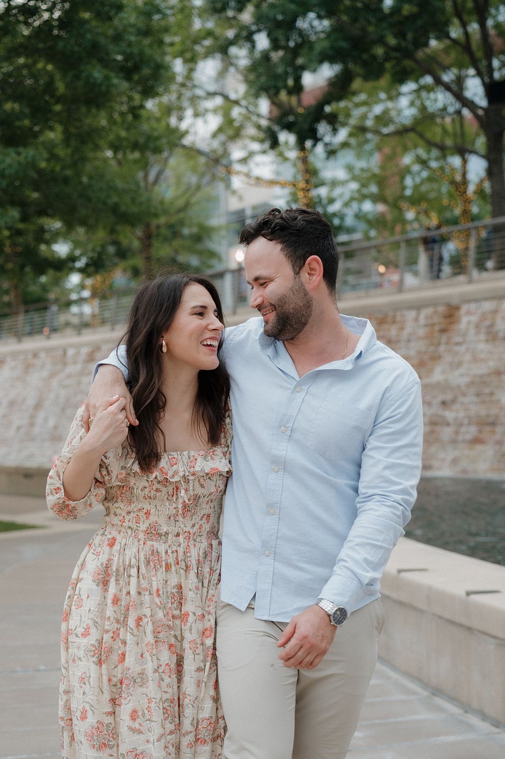 A couple shares a joyful moment together while standing outdoors in casual spring attire.