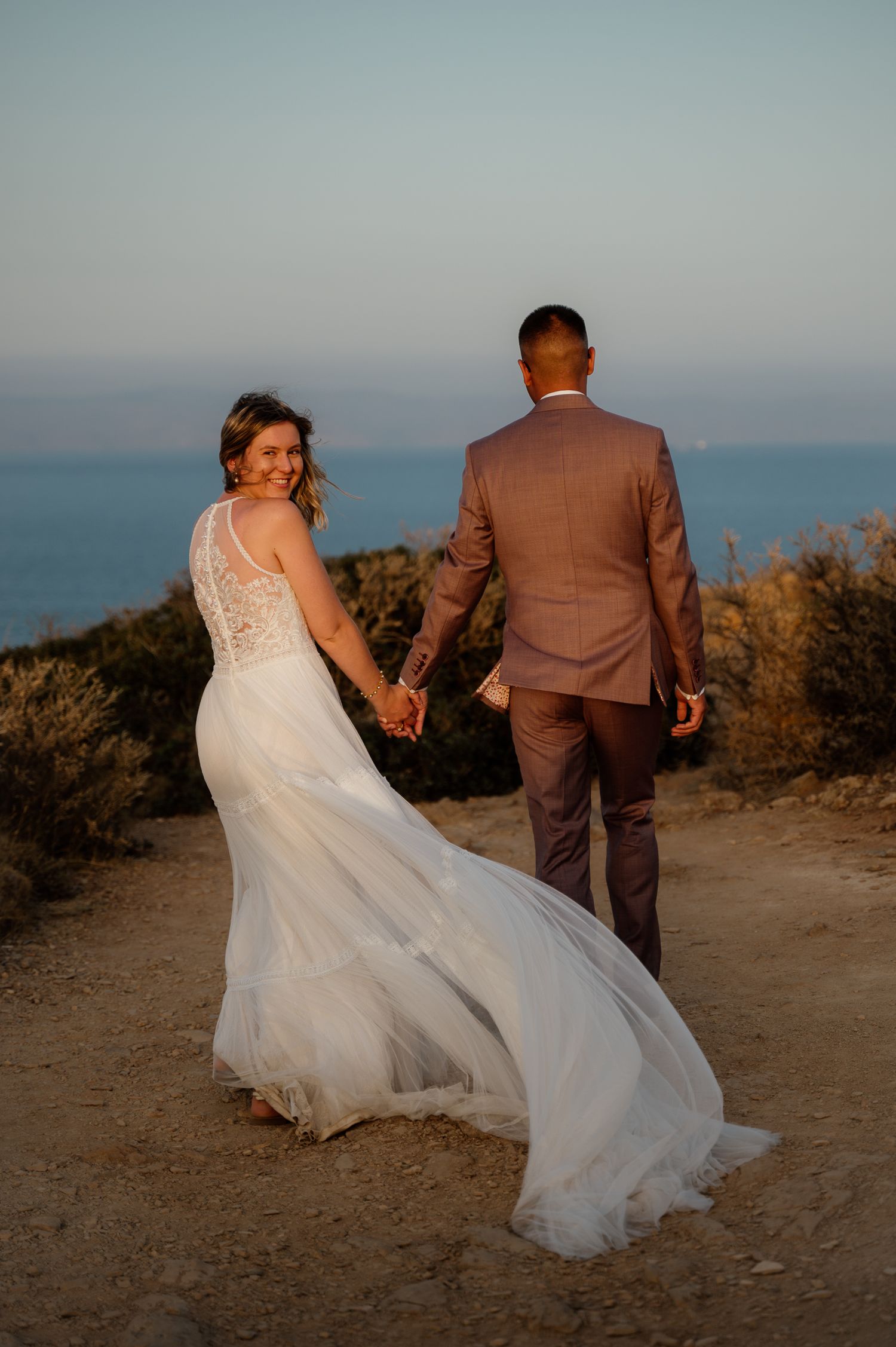 A candid photo of bride and groom walking holding hands and laughing at their next day photoshoot in Athens riviera Greece