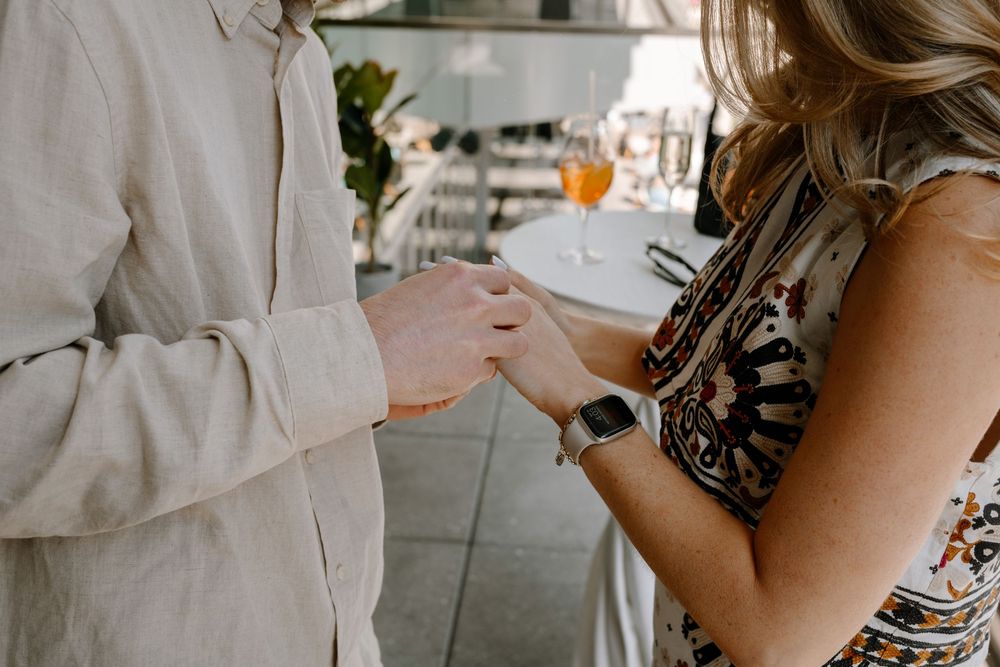 Two people sharing a romantic moment at an upscale outdoor restaurant overlooking a cityscape.