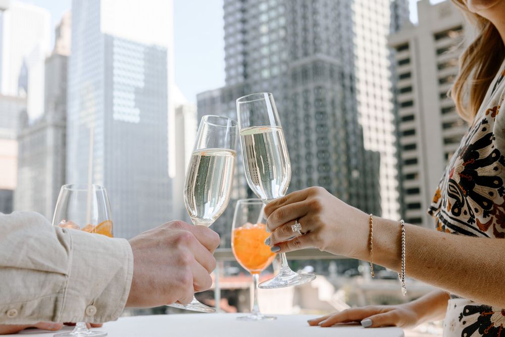 Two people toasting with champagne glasses against an urban city skyline background.