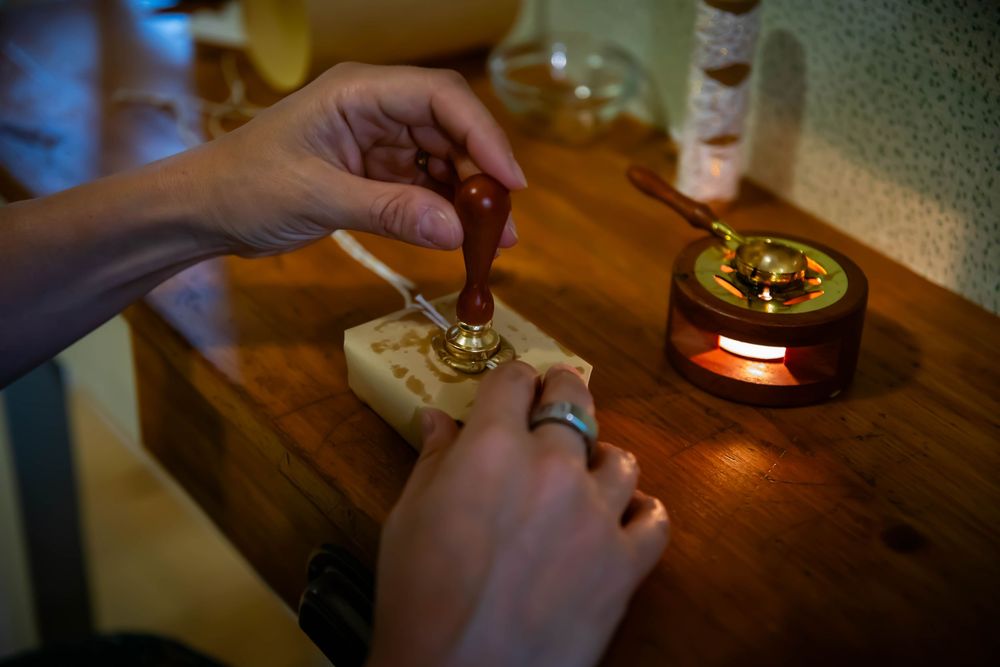 Hands carefully preparing essential oils or aromatherapy products on a wooden surface in warm ambient lighting.