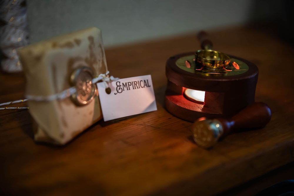 A brown candle holder and labeled package sitting on a wooden table in dim lighting.