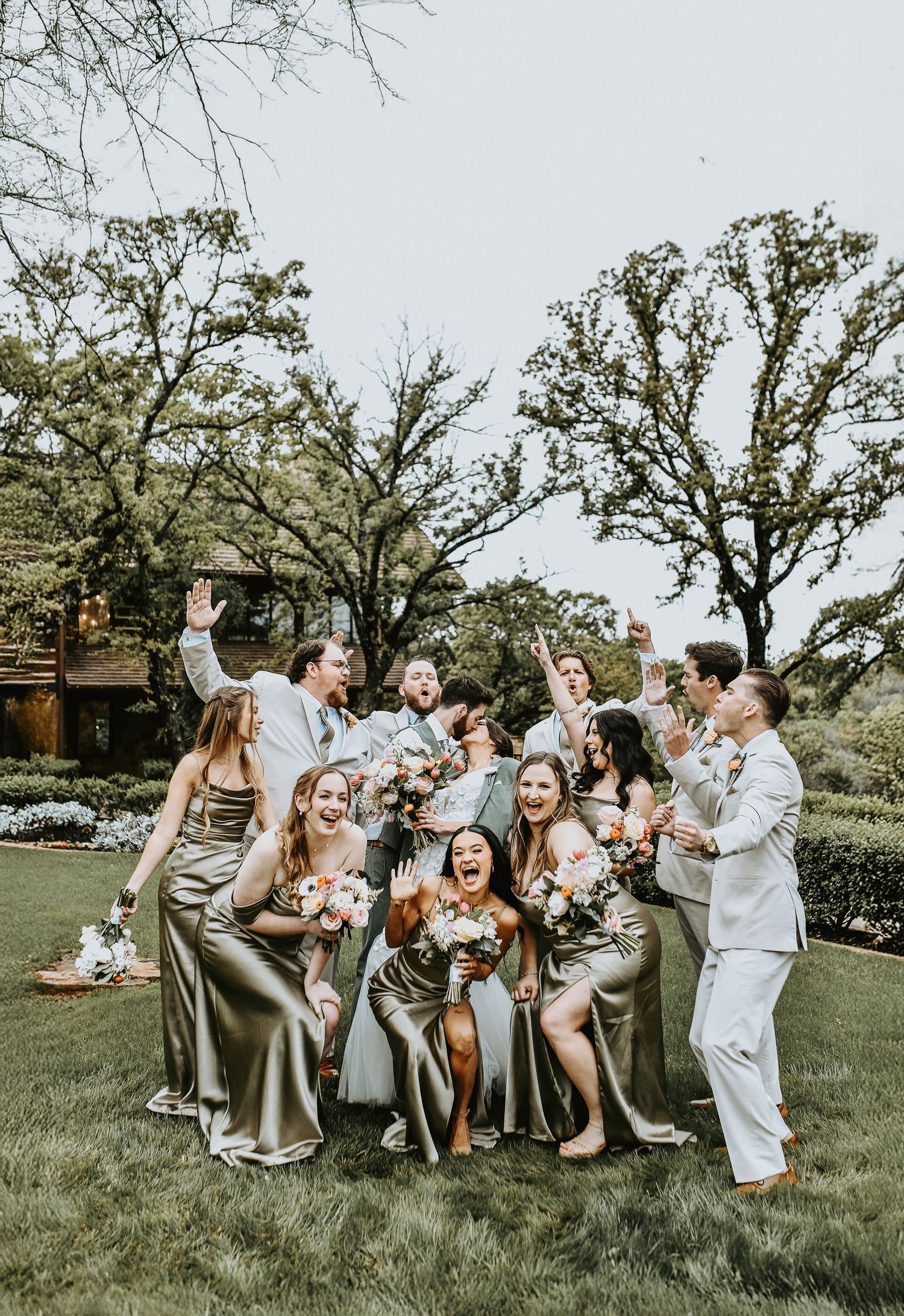 super fun and upbeat hyped up wedding party around the bride and groom as they kiss for their formal photos at the lodge at the springs