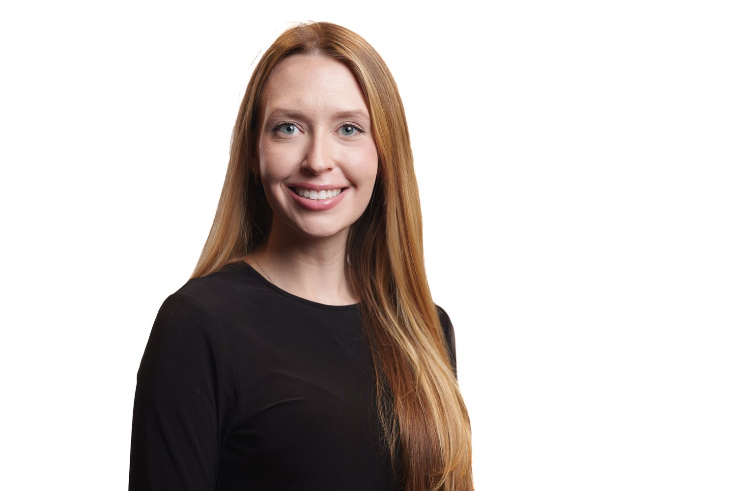 A person with long red hair wearing a black sweater smiles warmly against a white background.