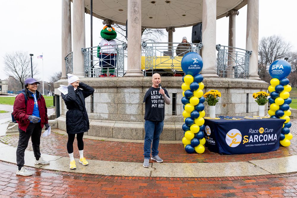Blue and yellow balloons decorate a stone gazebo in a park during a community event.