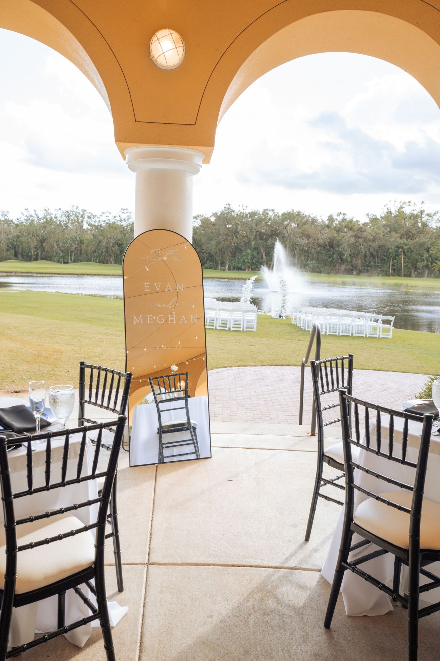 Outdoor wedding venue setup with black chairs overlooking a fountain and lake.