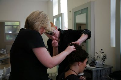 Hair stylist working on client's hair in bright salon setting.