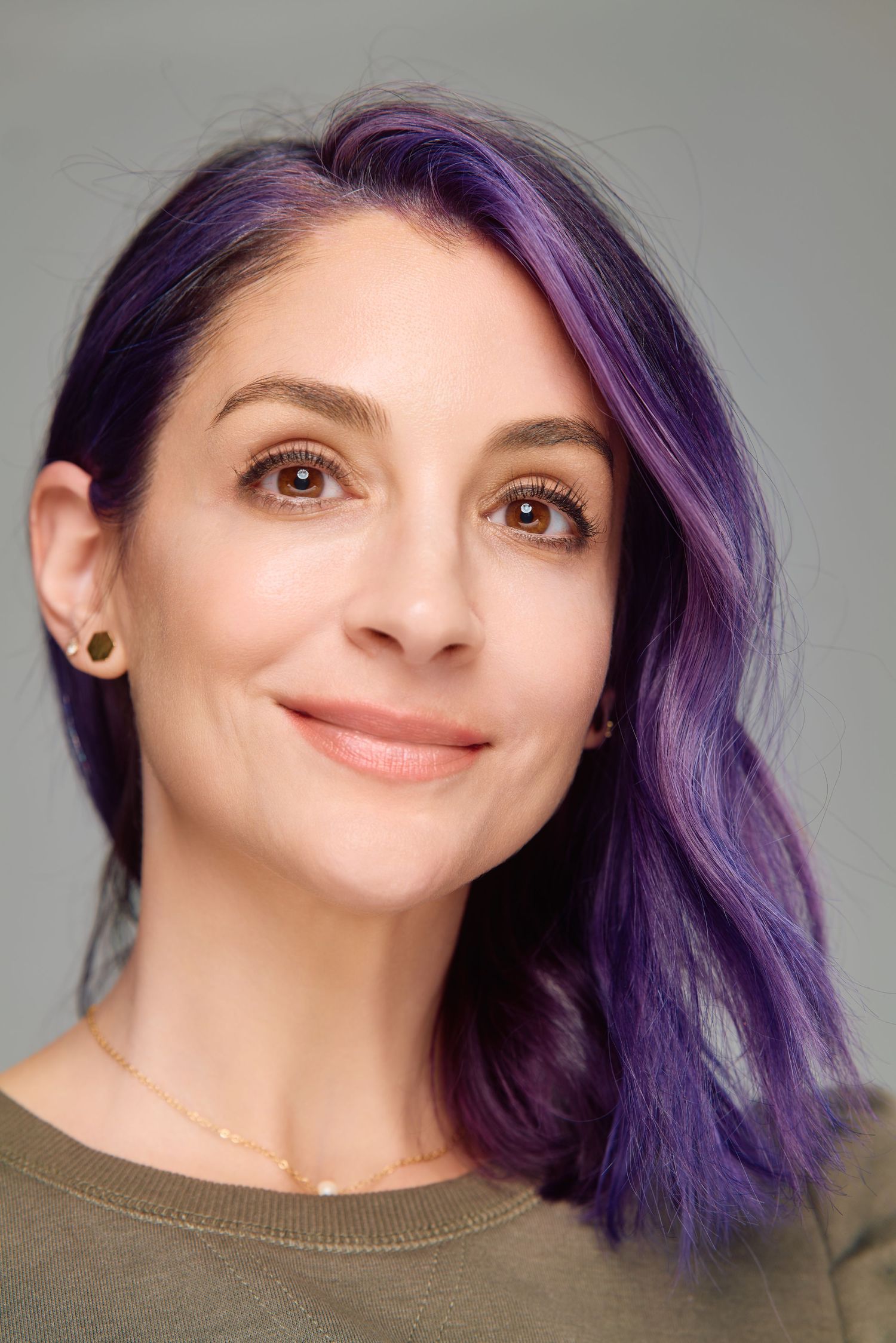 A close-up portrait showing vibrant purple hair and natural makeup.