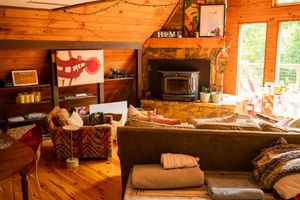 Warm wooden interior of a rustic cabin with natural light streaming through windows.