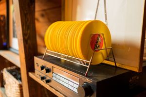Vintage yellow radio with stacked records displayed on wooden shelf.
