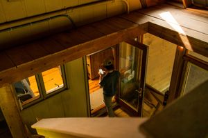 Person entering a dimly lit stairwell through a glass door at night.