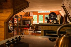 Cozy cabin interior with wooden beams, sitting area and vintage barrel decor.