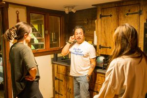 People having a conversation in a rustic wooden room with vintage cabinets.