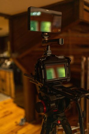 Professional camera equipment and stabilizers set up on wooden surfaces in low light.