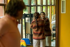 Two people reviewing footage or rehearsing scene in interior setting with window light.