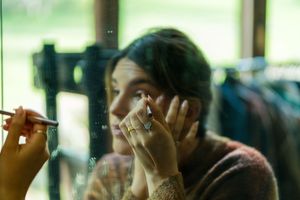 Person adjusting camera settings while filming in artistic lighting conditions.