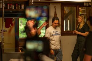 Camera crew filming a scene in a dimly lit bar or restaurant interior.