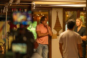 Behind-the-scenes film crew captures interaction between people in a dimly lit restaurant setting with warm lighting.