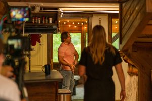 Production crew members working in dimly lit interior space with ambient lighting.