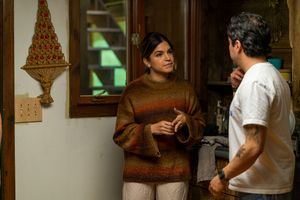 Two people engaged in conversation during film production in cozy interior setting.