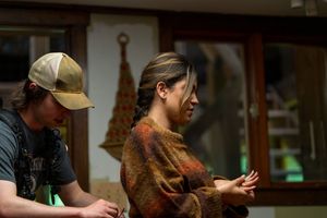 Two people in casual attire working together in dimly lit room with wooden furnishings.