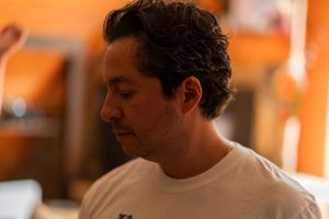 Profile view of someone in a white t-shirt against an orange wall.
