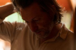 Moody low-light portrait of person in white collar shirt.