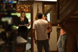 Film production team shooting a scene with crew members and talent in a cozy restaurant interior.