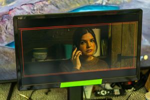 A camera monitor displays footage of a person in a dark, moody scene.
