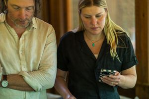 Two people in casual attire collaborating while one checks their phone.