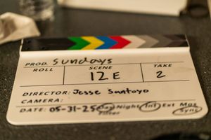 A film slate board with production details displays against a dark background.