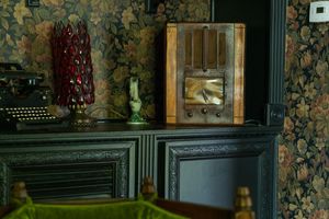 Vintage typewriter and display case against floral wallpaper in an antique setting.