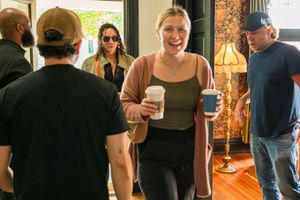 People standing together indoors near a window with natural light streaming in and casual attire.