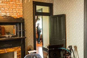 Rustic interior room with exposed brick wall, wooden furniture and open doorway showing movement in adjacent space.