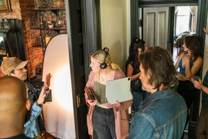 Production crew working together in hallway with exposed brick wall and natural lighting.