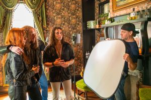 Three people collaborating on a photo shoot with professional lighting equipment in a vintage-styled room.