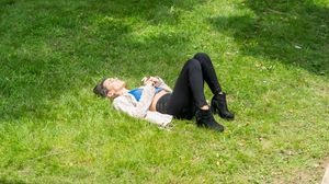 A person resting on green grass while enjoying the sunshine on a warm day.