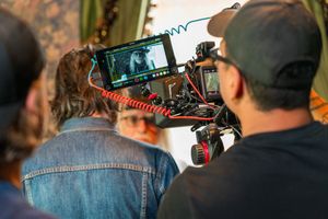 Camera operators monitor a video screen while filming with a professional cinema camera rig on a film production set.