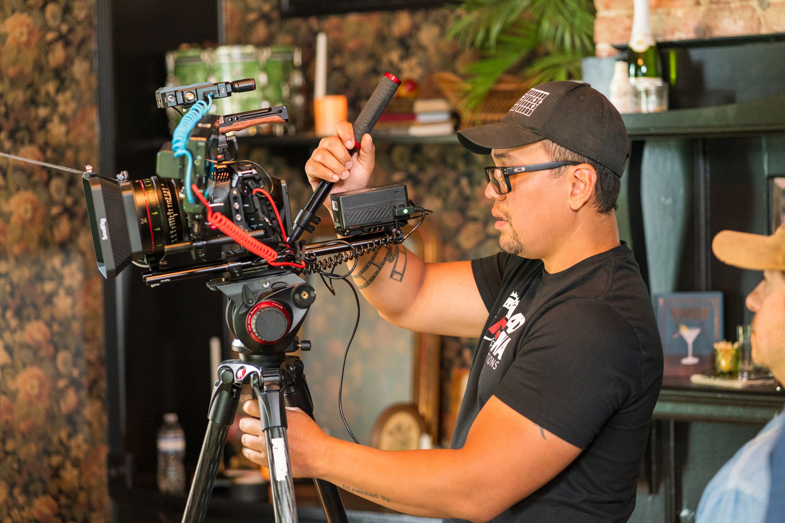 Camera operator adjusts professional filmmaking equipment while shooting in a commercial setting.